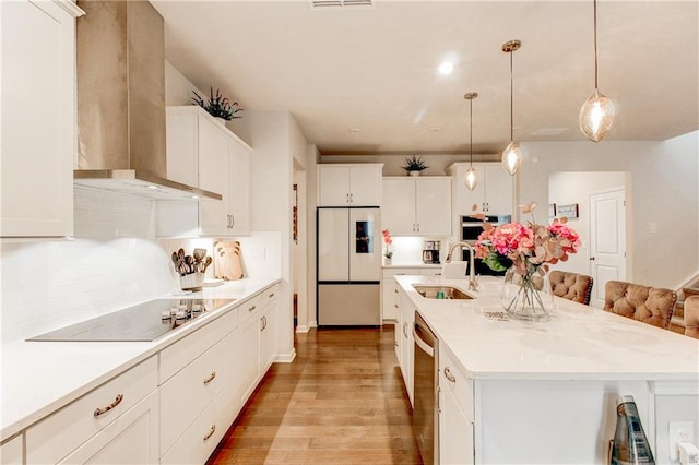 kitchen featuring light hardwood / wood-style floors, sink, an island with sink, white cabinets, and appliances with stainless steel finishes