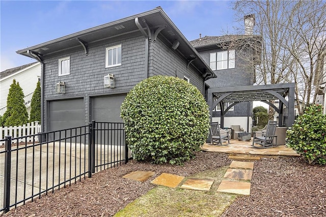 exterior space with a garage, a pergola, and a patio