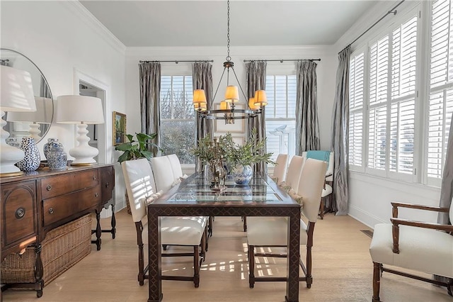 dining area with crown molding, a notable chandelier, and light hardwood / wood-style flooring