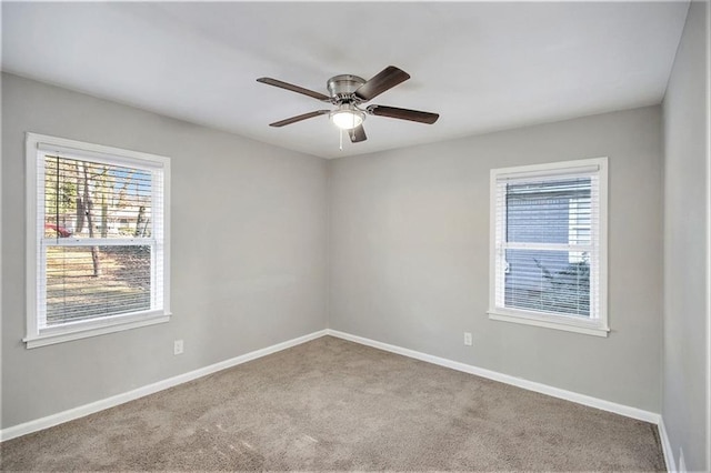 spare room featuring a healthy amount of sunlight, ceiling fan, and light carpet