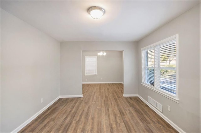 unfurnished room with an inviting chandelier and wood-type flooring