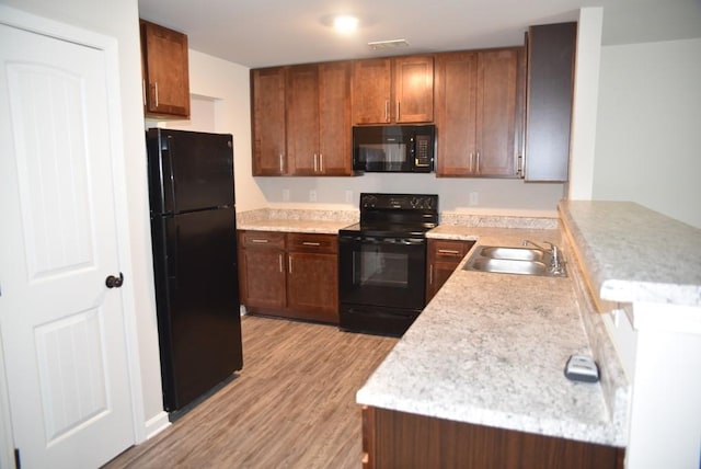 kitchen with kitchen peninsula, sink, light hardwood / wood-style floors, and black appliances