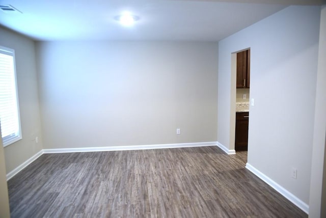 empty room with plenty of natural light and dark wood-type flooring