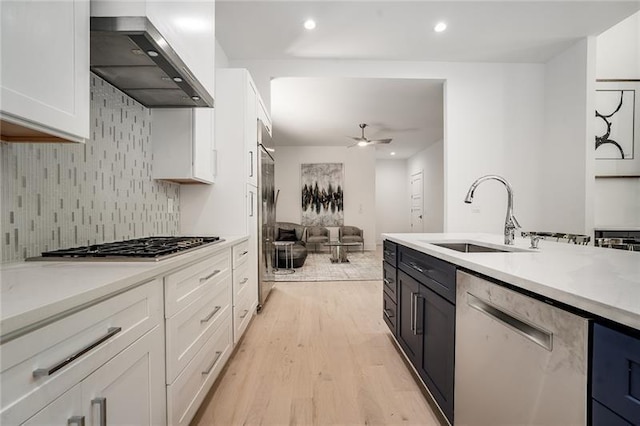 kitchen with white cabinetry, light hardwood / wood-style flooring, white dishwasher, and wall chimney exhaust hood