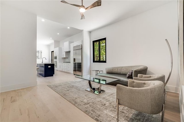 living room featuring sink, ceiling fan, and light hardwood / wood-style floors