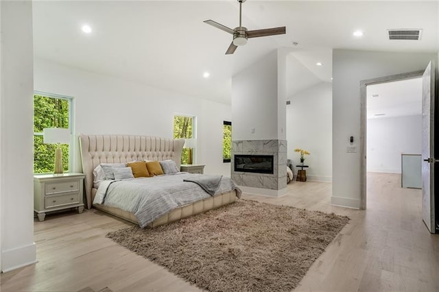 bedroom with high vaulted ceiling, a fireplace, ceiling fan, and light wood-type flooring