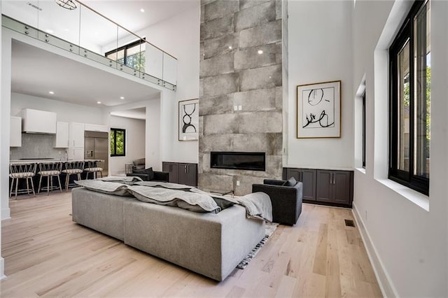 living room with light wood-type flooring, a large fireplace, and a healthy amount of sunlight