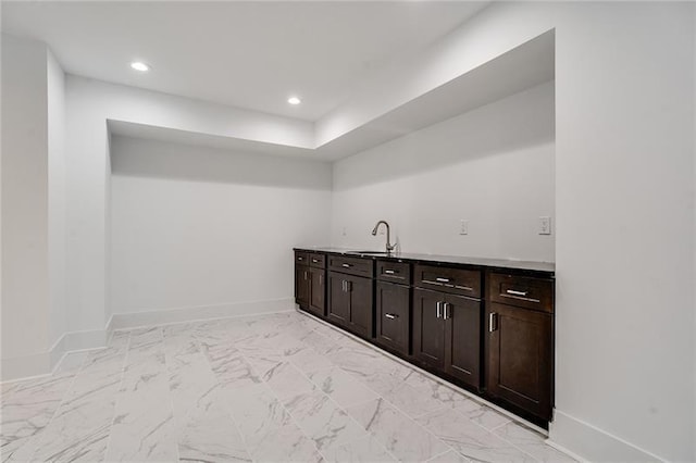 bar featuring light tile patterned floors, dark brown cabinetry, and sink