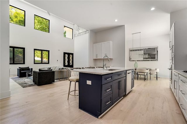 kitchen with white cabinets, a kitchen breakfast bar, light hardwood / wood-style flooring, and a center island with sink