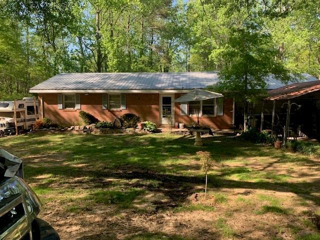 back of house with metal roof and a lawn
