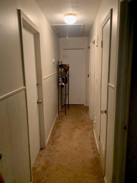 hall featuring baseboards and light colored carpet