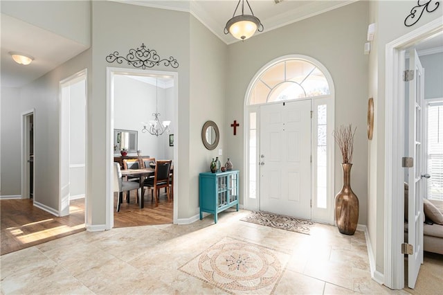 entryway with a towering ceiling, ornamental molding, and a chandelier