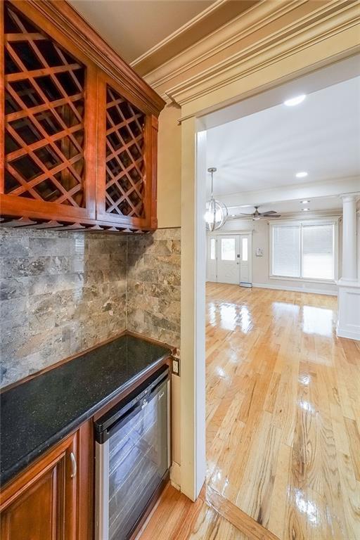3416 Harrison Rd, Atlanta, GA 30344 - indoor dry bar featuring wine cooler, ceiling fan, light wood finished floors, and decorative backsplash