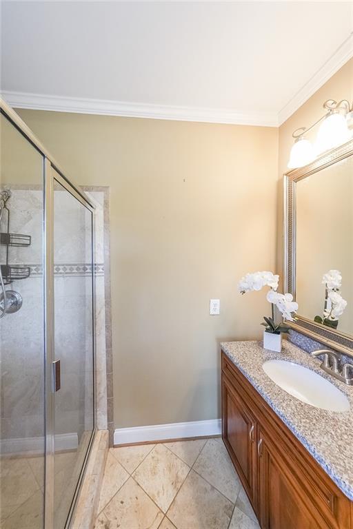 3416 Harrison Rd, Atlanta, GA 30344 - bathroom featuring a shower stall, crown molding, vanity, tile patterned flooring, and baseboards