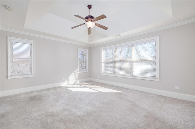 unfurnished room with a tray ceiling, ceiling fan, crown molding, and light colored carpet