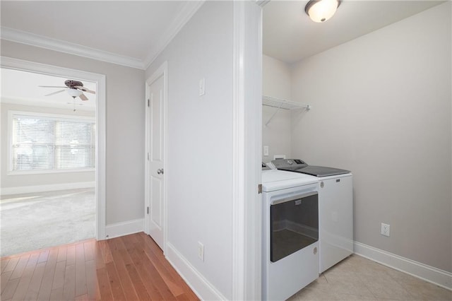 clothes washing area featuring light wood-type flooring, washing machine and dryer, ceiling fan, and ornamental molding