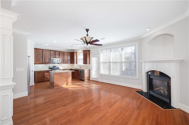 kitchen featuring a center island, decorative backsplash, ornamental molding, appliances with stainless steel finishes, and wood-type flooring
