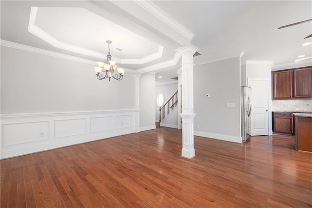 interior space featuring dark wood-type flooring, a raised ceiling, decorative columns, crown molding, and a chandelier