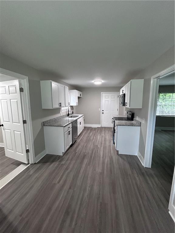 209 Trade Way, Dalton, GA 30721 - kitchen featuring white cabinets, stainless steel appliances, a sink, baseboards, and dark wood-type flooring