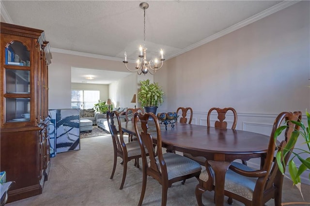 dining area with a wainscoted wall, carpet floors, ornamental molding, a textured ceiling, and a notable chandelier