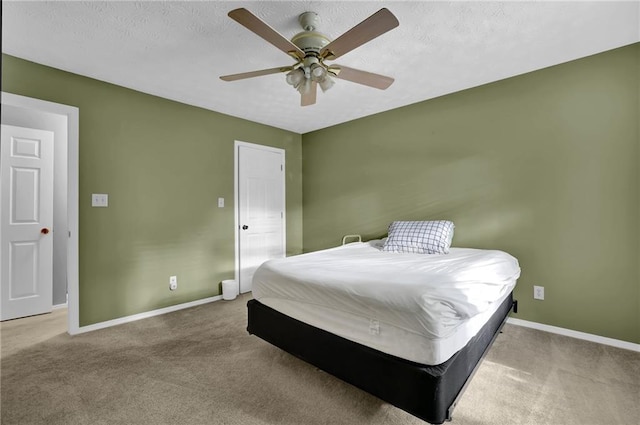 bedroom with ceiling fan, light colored carpet, and a textured ceiling