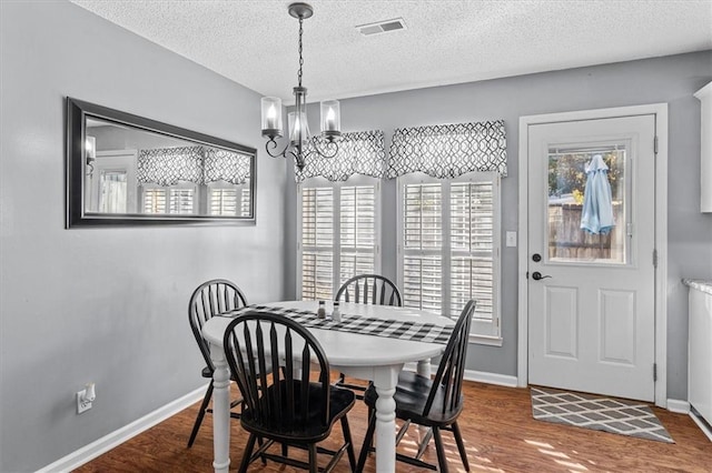 dining space with a chandelier, dark hardwood / wood-style floors, and a textured ceiling