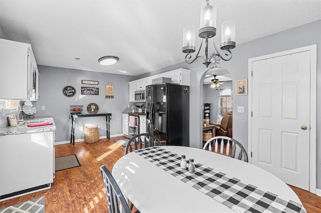 dining area featuring ceiling fan with notable chandelier, a textured ceiling, and hardwood / wood-style flooring