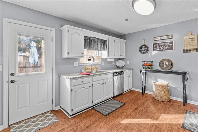 kitchen with a textured ceiling, dishwasher, white cabinetry, light hardwood / wood-style floors, and sink