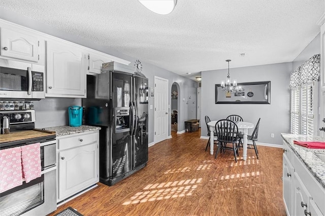 kitchen featuring appliances with stainless steel finishes, hanging light fixtures, a textured ceiling, a chandelier, and white cabinets