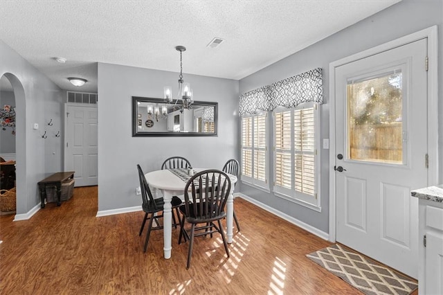 dining space with an inviting chandelier, a textured ceiling, and hardwood / wood-style flooring