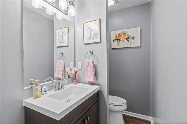 bathroom featuring a textured ceiling, toilet, and vanity