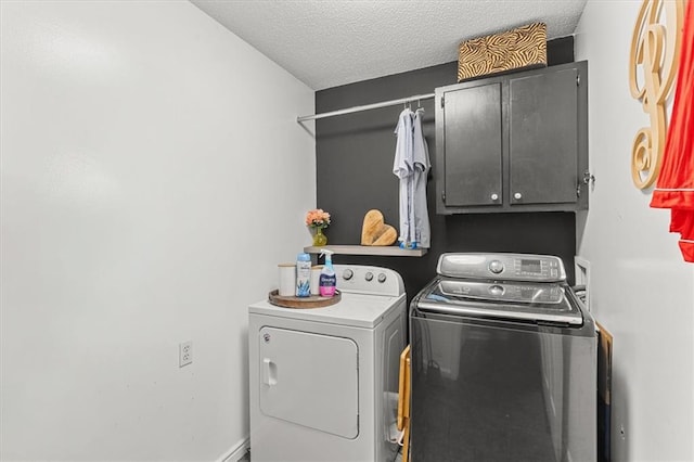 clothes washing area featuring washer and clothes dryer, a textured ceiling, and cabinets