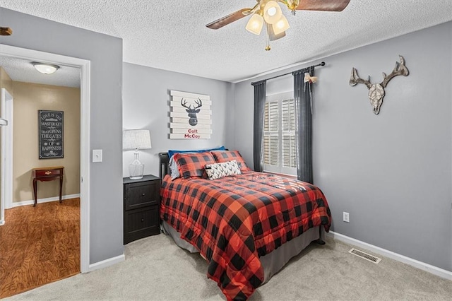 bedroom featuring ceiling fan, light colored carpet, and a textured ceiling