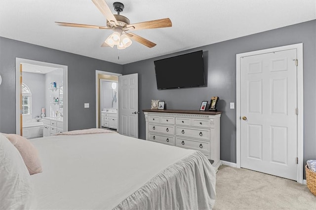 bedroom featuring light carpet, ceiling fan, and ensuite bathroom