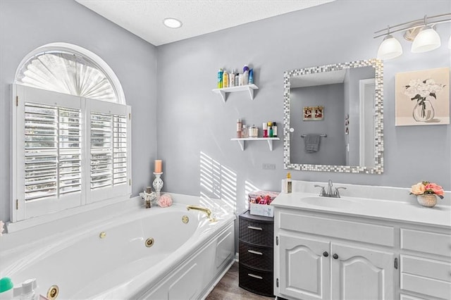 bathroom featuring a bath, a textured ceiling, and vanity