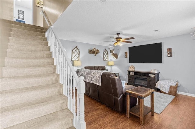 living room with ceiling fan, a fireplace, and hardwood / wood-style flooring