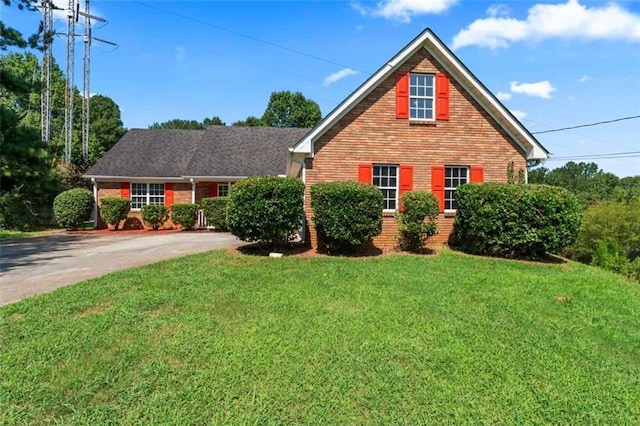 traditional home with a front yard, brick siding, and driveway