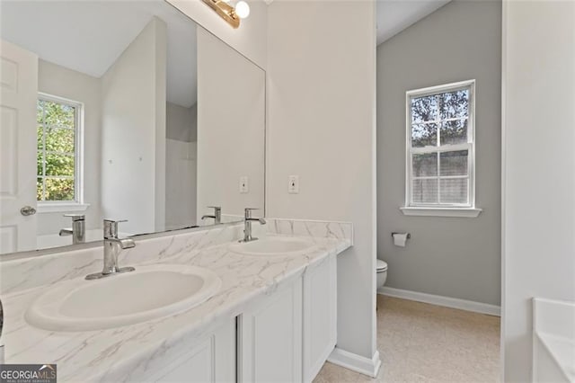 full bath with baseboards, a sink, toilet, and double vanity