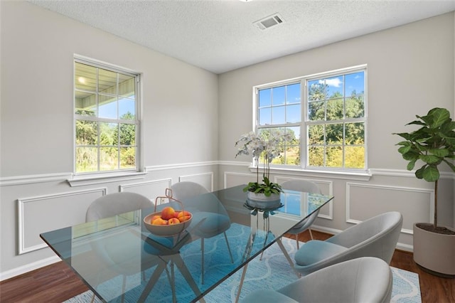 sitting room featuring a textured ceiling, visible vents, wood finished floors, and wainscoting