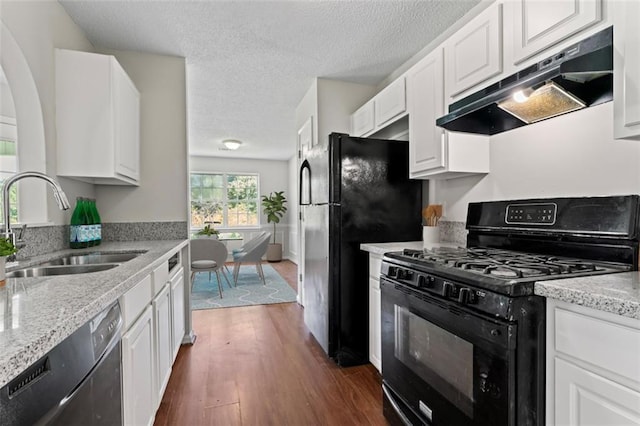 kitchen with dark wood finished floors, white cabinetry, a sink, under cabinet range hood, and black appliances