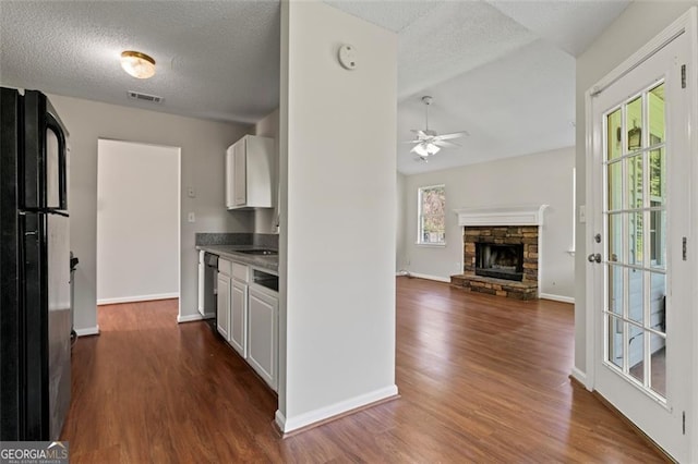 kitchen featuring a textured ceiling, dark wood-style flooring, freestanding refrigerator, and white cabinetry