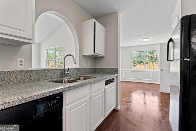 kitchen featuring black appliances, a sink, light stone countertops, and white cabinets