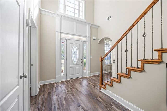 entryway featuring a healthy amount of sunlight, dark wood-type flooring, and a high ceiling