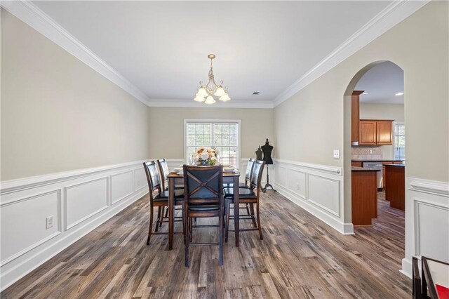 dining room featuring dark hardwood / wood-style flooring, ornamental molding, and a chandelier