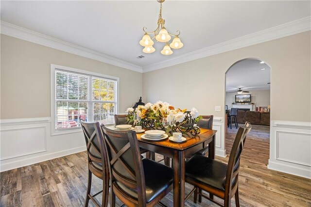 dining area featuring hardwood / wood-style floors, ceiling fan with notable chandelier, and crown molding