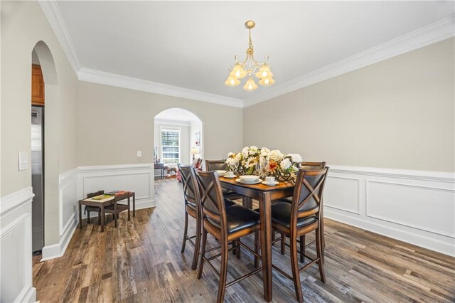 dining space featuring dark hardwood / wood-style flooring, an inviting chandelier, and ornamental molding