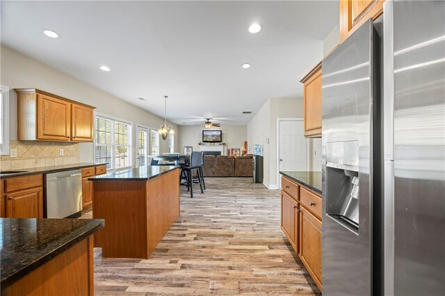 kitchen with ceiling fan, stainless steel appliances, pendant lighting, light hardwood / wood-style floors, and a kitchen island