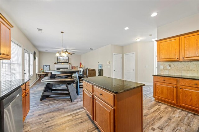 kitchen with backsplash, dark stone counters, light hardwood / wood-style flooring, dishwasher, and a kitchen island