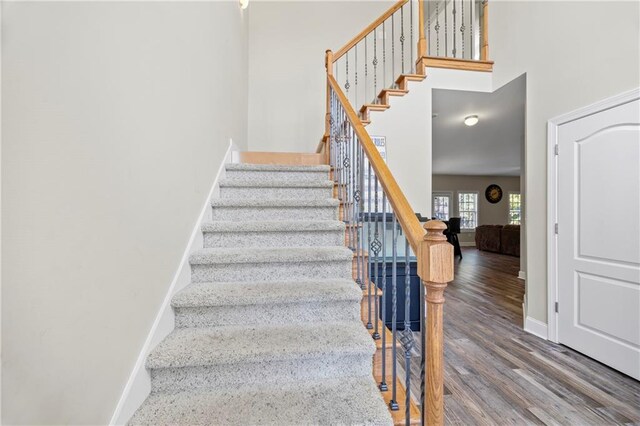 stairs with hardwood / wood-style floors and a high ceiling