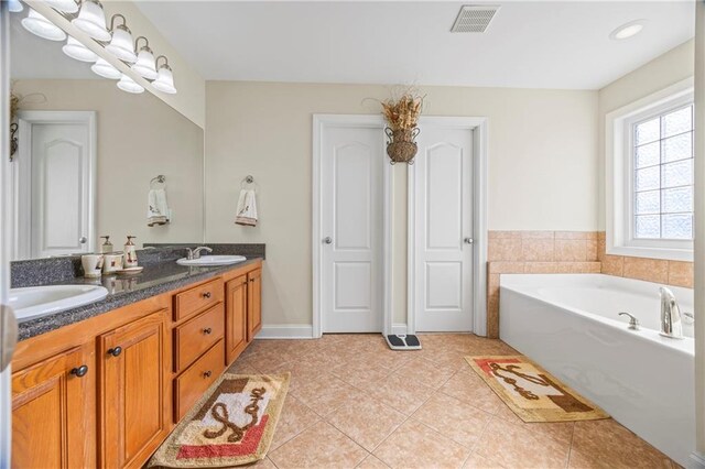 bathroom featuring tile patterned floors, a tub, and vanity